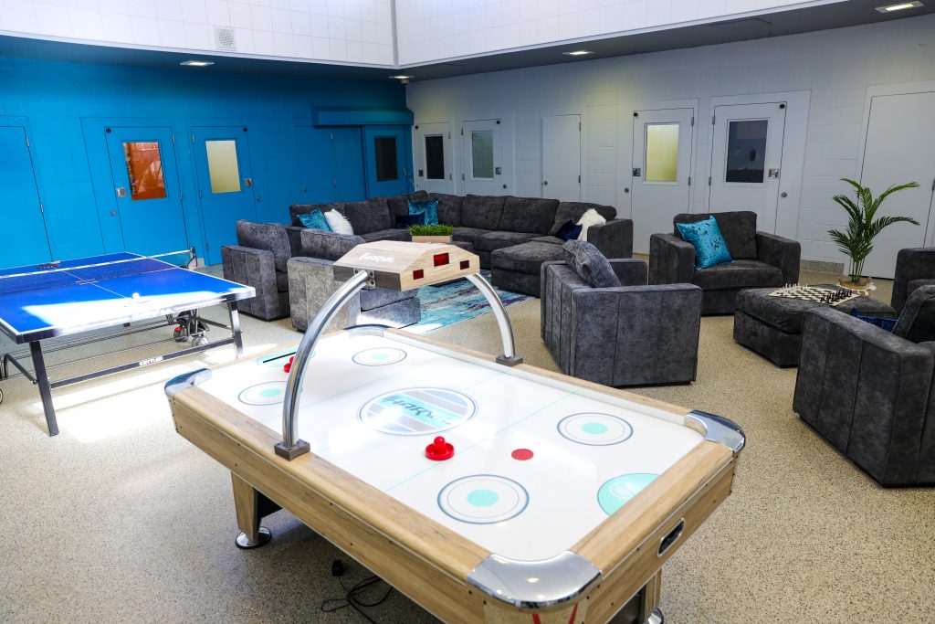 A game room featuring air hockey, table tennis and a comfortable seating area. 